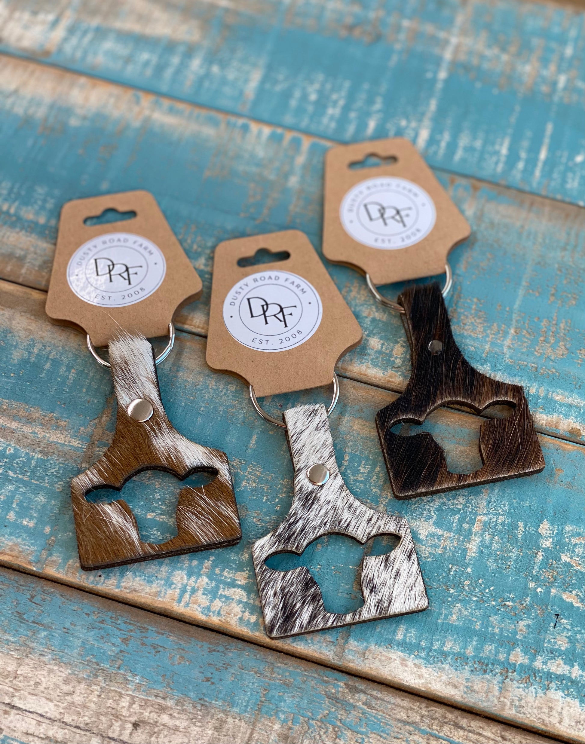Cow ear tag keychains made from genuine cowhide with a cowhead cutout.