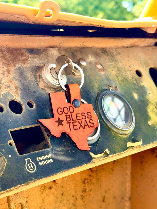 Keychain with 'God Bless Texas' on a mechanical surface