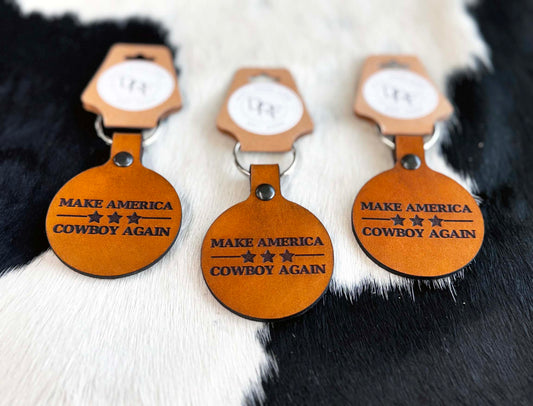Three brown leather keychains with embossed text and stars, displayed on a furry surface.
