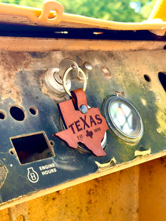 Leather keychain shaped like the state of Texas attached to a piece of machinery.
